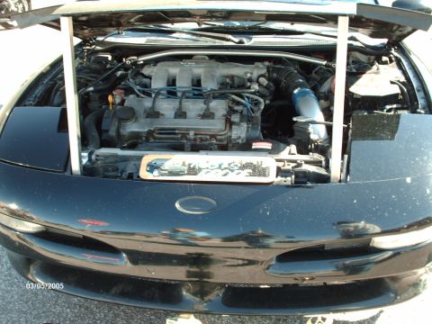 1995 Ford Probe - The engine bay of a car is visible with the hood open, a decorative plate with a car illustration.