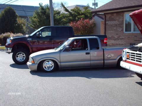 1995 Ford Probe - Multiple vehicles parked on asphalt, including a silver pickup truck with custom wheels and suspension.