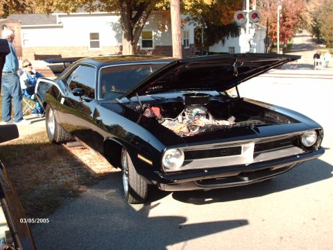 1995 Ford Probe - A black 1970 Plymouth Barracuda is displayed with its hood open at an outdoor car show.