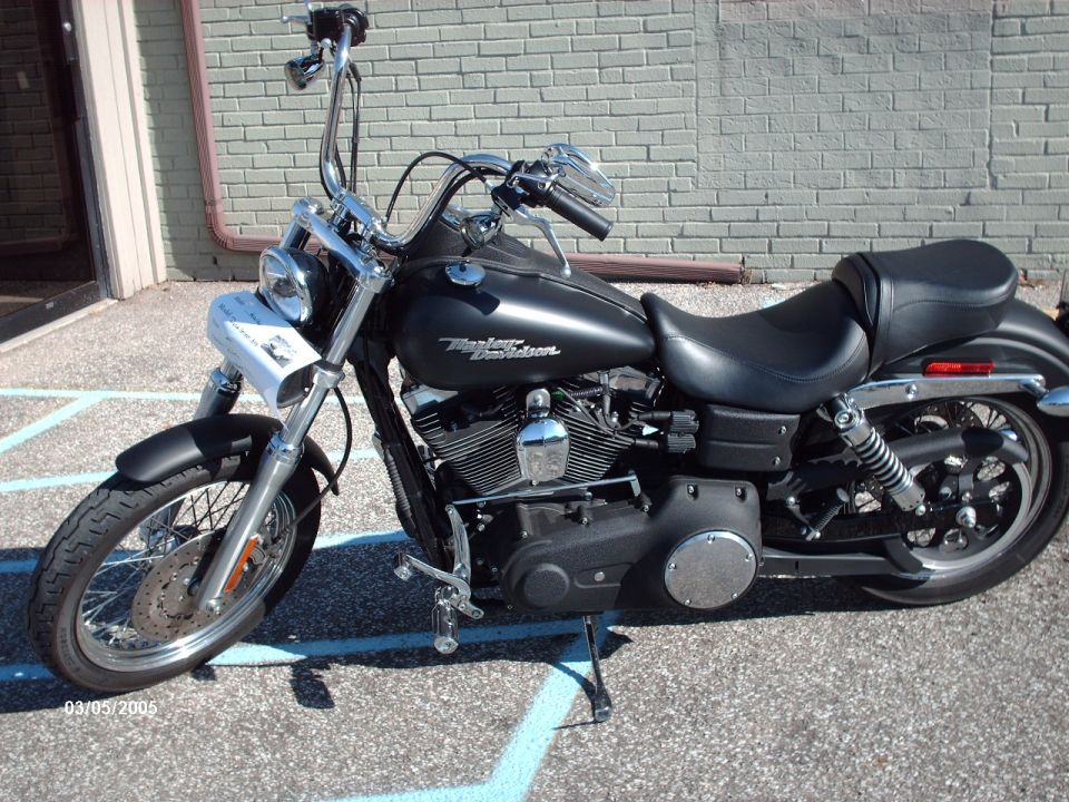 Black Harley-Davidson motorcycle parked outside, showing the front wheel, engine, and seat
