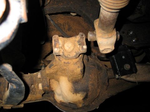 1989 Ford F-150 - Underside view of rusty drivetrain components, including a differential and driveshaft U-joints.