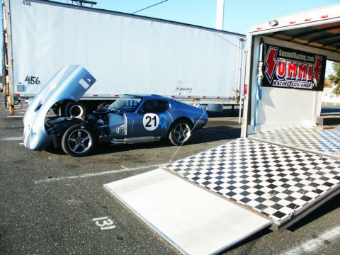 2001 Mercury Grand Marquis - A blue race car is parked next to a trailer with its hood open, revealing the engine.