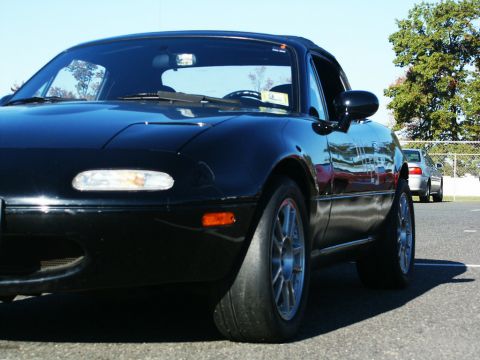 2001 Mercury Grand Marquis - A black convertible sports car is parked on asphalt with another car in the background.