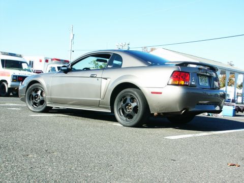 2001 Mercury Grand Marquis - Gray Ford Mustang coupe with a spoiler is parked on asphalt.