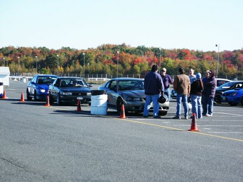 2001 Mercury Grand Marquis - A group of people stand around a gray Ford Mustang at an event with other cars visible.