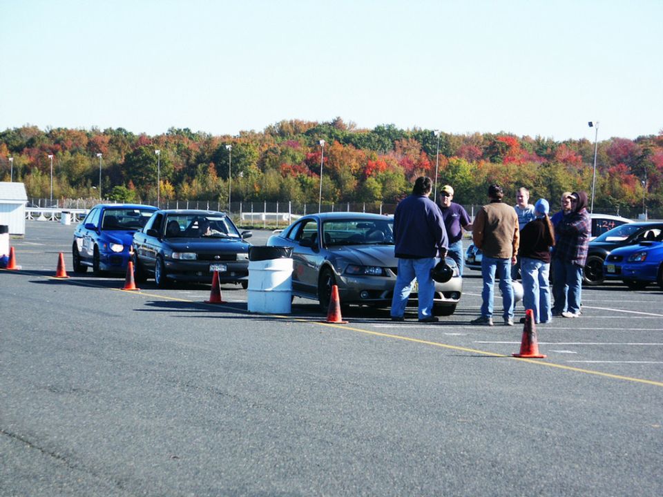 Gray Ford Mustang with a dark grille and headlights, parked on asphalt with orange cones