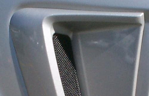 Side scoop mesh cover on a vehicle, showing a black mesh insert within a gray housing