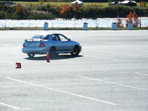 2001 Mercury Grand Marquis - A light blue sedan navigates a course marked by traffic cones on a paved lot.