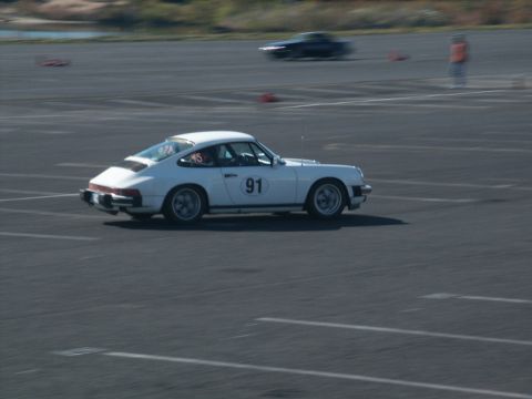 2001 Mercury Grand Marquis - A white Porsche 911 with racing number 91 is seen on a race track, with another dark car in the background.