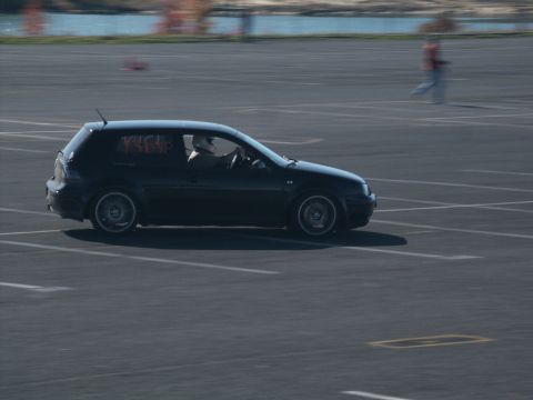 2001 Mercury Grand Marquis - A black hatchback car with racing decals on its window is captured in motion on a paved surface.