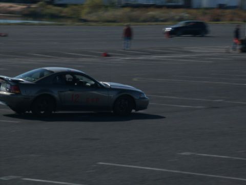 2001 Mercury Grand Marquis - A silver 2001 Ford Mustang GT coupe, identified by its body style and racing numbers, participates in an event on a paved track.