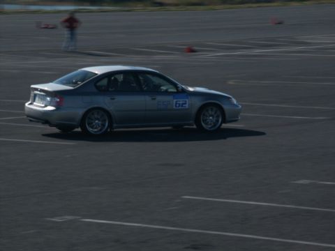 2001 Mercury Grand Marquis - Silver sedan with racing number 62 on the door is seen on a paved track.