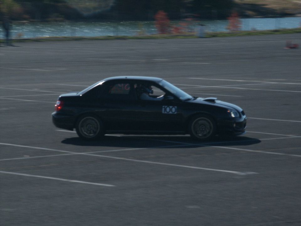 Black sedan with number 100 on the door driving on a paved track
