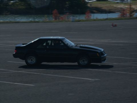 2001 Mercury Grand Marquis - A black coupe with a spoiler and hood scoop is captured in motion on a paved surface.