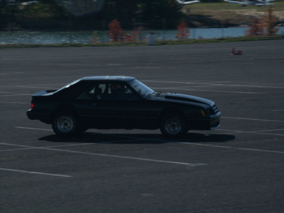 Black coupe with a spoiler and hood scoop, seen from the side