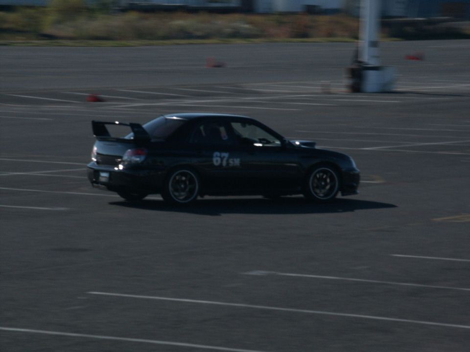 Black Subaru WRX STI with racing numbers '67 SM' and a large rear spoiler on a track