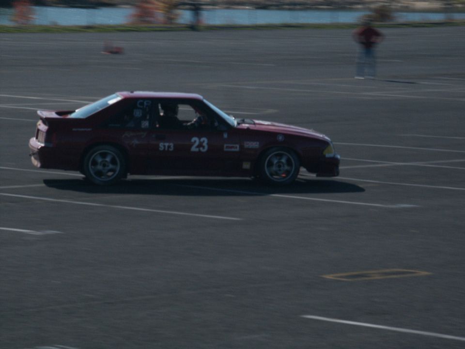 Red coupe with racing decals and number 23 on the door, driving on a track