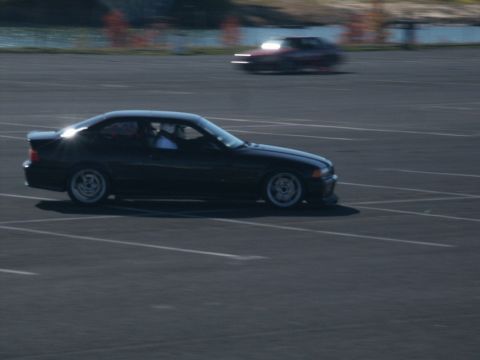 2001 Mercury Grand Marquis - A black coupe is captured in motion on a track, with another vehicle visible in the distance.
