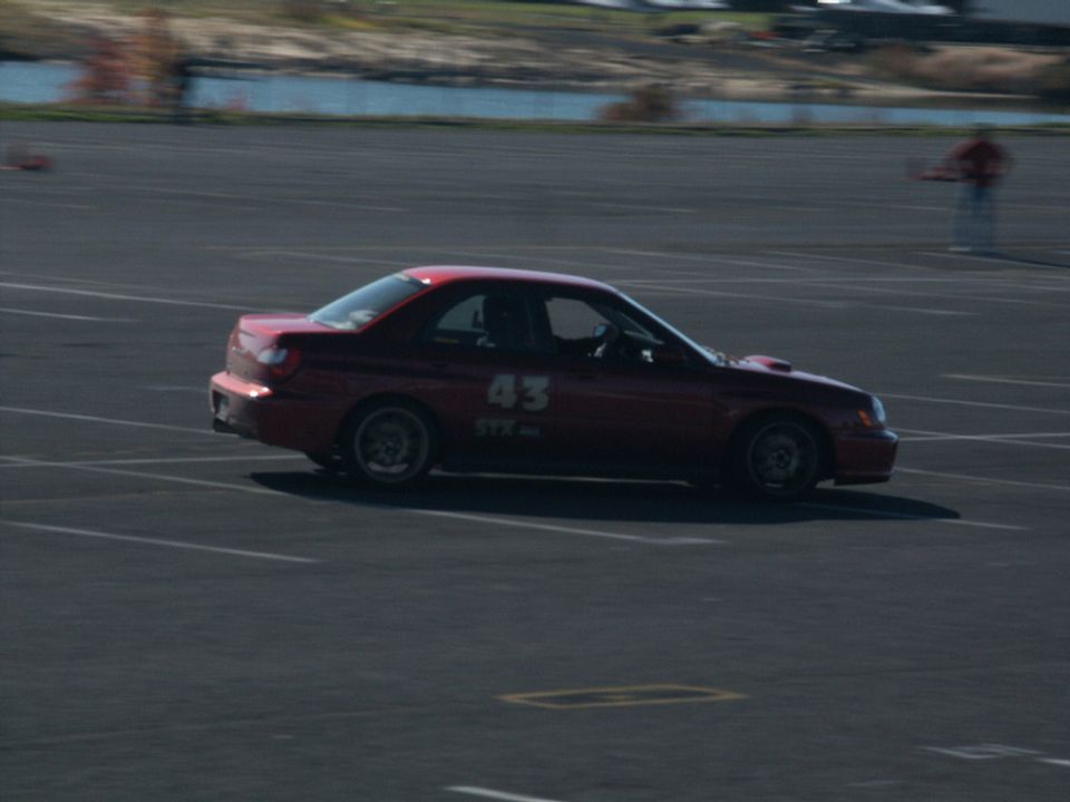 Red sedan with racing number 43 and STX decal on its side, viewed from the left
