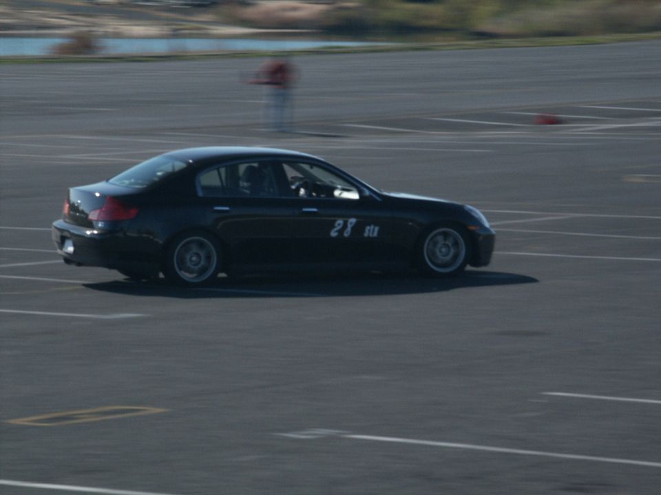 Black sedan with racing number 28 on its side, viewed from the side on a track