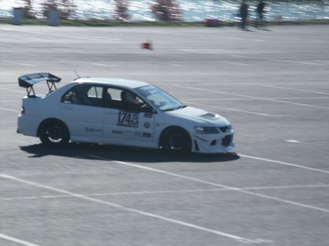 2001 Mercury Grand Marquis - A white sedan, possibly a Mitsubishi Lancer Evolution, competes on a race track with a prominent rear spoiler and racing decals.