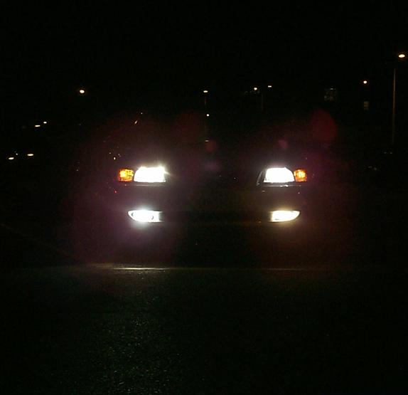 Car front at night, headlights and fog lights illuminated