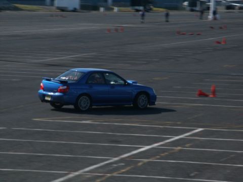 2001 Mercury Grand Marquis - A blue Subaru Impreza WRX navigates a cone course on a paved track.