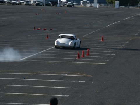 2001 Mercury Grand Marquis - A white sports car is seen from behind, kicking up smoke during a timed event on a paved lot.