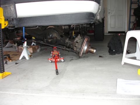 1996 Ford Bronco - The rear axle of a 1996 Ford Bronco is disassembled and supported by jack stands and a floor jack in a garage.