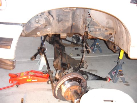 1996 Ford Bronco - Vehicle suspension components are supported by jack stands and a hydraulic jack during maintenance.