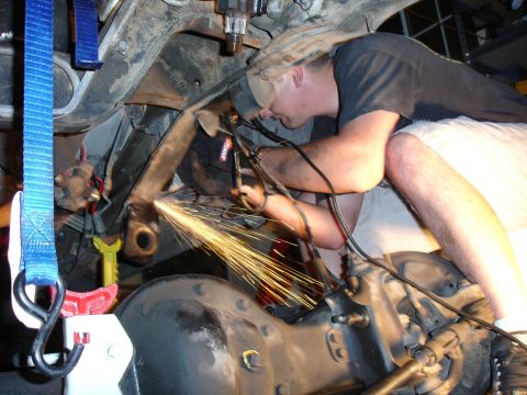 1996 Ford Bronco - Working on the undercarriage of a vehicle, sparks fly as a grinder is used on a suspension component.