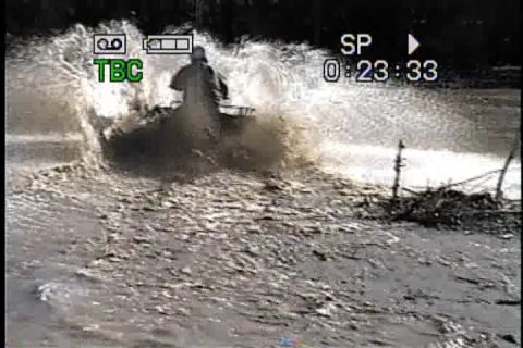 1989 Ford Bronco - An ATV rider creates a large splash as they ride through a muddy body of water.