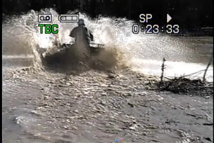 Person on an ATV splashing through muddy water. Video timestamp 0:23:33