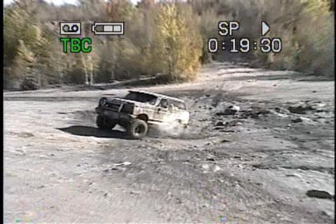 1989 Ford Bronco - A 1987 Ford Bronco navigates a dirt path, with trees in the background and a timestamp overlay.