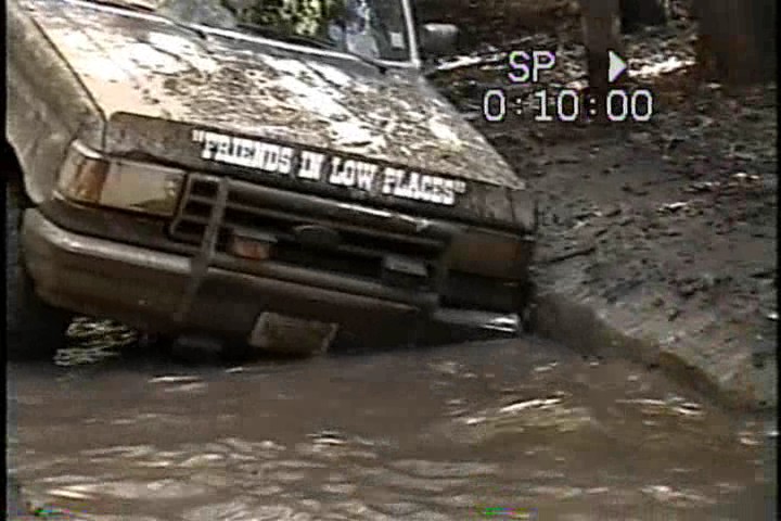 Muddy truck with "FRIENDS IN LOW PLACES" on hood stuck in water