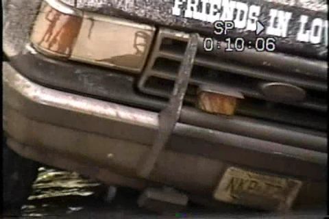 1989 Ford Bronco - A close-up view of the front of a dark-colored Ford Bronco, showing its grille and bumper.