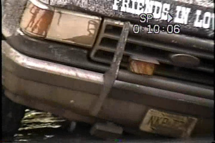 Front bumper and grille of a dark 1987 Ford Bronco with a dented bumper and a New Jersey license plate