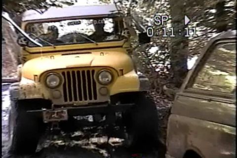 1989 Ford Bronco - A yellow Jeep CJ navigates an off-road trail, with another vehicle visible to its side.