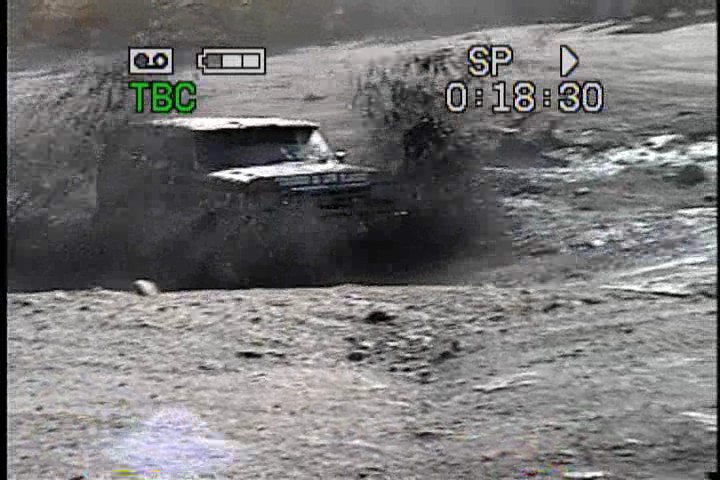 Dark 1987 Ford Bronco driving through mud, splashing water