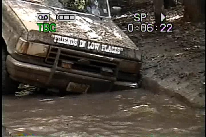 Brown 1989 Ford Bronco front view stuck in mud, "Friends in Low Places" decal on hood