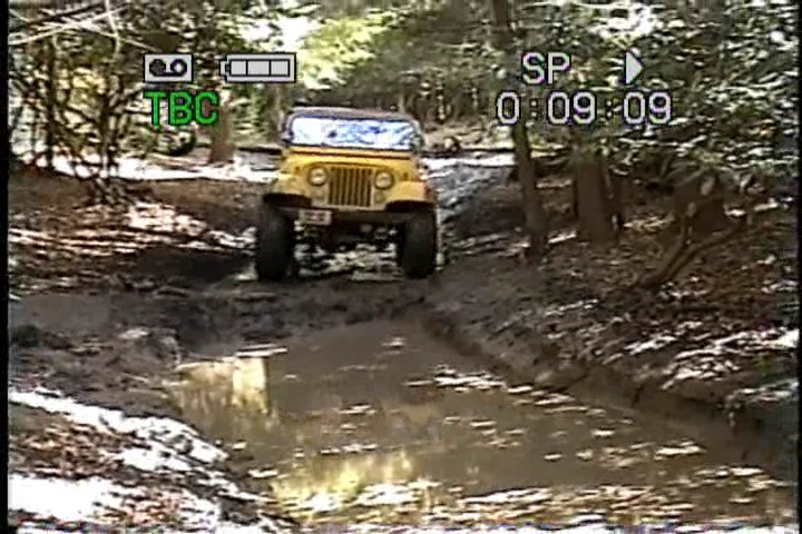 Yellow Jeep driving through a muddy trail
