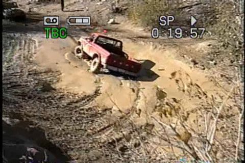 1989 Ford Bronco - Red pickup truck navigates a muddy trail, captured on video with a timestamp.
