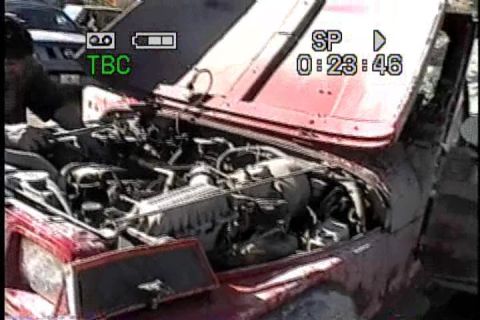 1989 Ford Bronco - View of a red vehicle's engine compartment with the hood open, showing the engine and surrounding components.