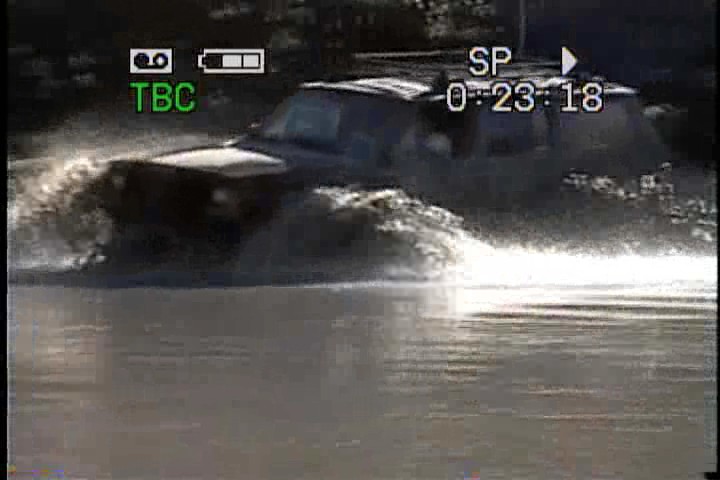SUV splashing through water, camera timestamp reads 0:23:18