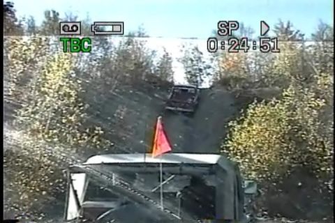 1989 Ford Bronco - Two vehicles navigate a steep dirt incline surrounded by trees.