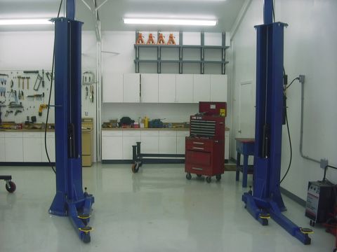 1990 Ford Mustang - A clean garage space equipped with a car lift, tool storage, and workbench.