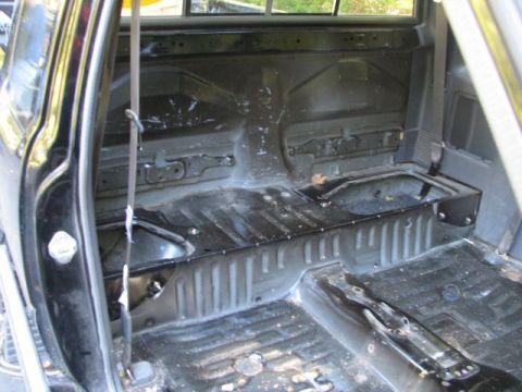 1994 Toyota Tacoma - The interior of the truck is stripped down, revealing the bare metal floor and rear cabin structure.