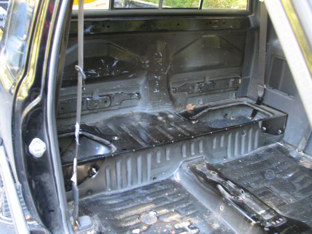 Interior of a truck with seats removed, showing the bare floor and rear wall