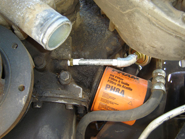 Orange Fram PH8A oil filter and braided oil line on a greasy engine block