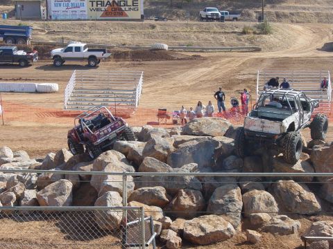 1986 Ford Bronco - Modified off-road vehicles tackle a challenging rock obstacle course during an event.